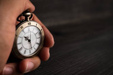 Erkekler elleri bir cep saati ve siyah bir arka plan tutun.