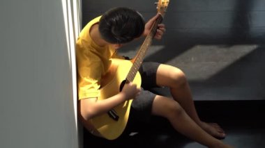 Evde gitar çalan ve gitar çalan küçük bir Asyalı çocuk müzik teli enstrümanları, müzik eğitimi konsepti, ilham kaynağı, genç sanat okulu öğrencisi.