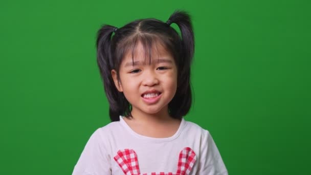 在绿色的画面背景上描绘着快乐 微笑和滑稽的亚洲小女孩 一个小孩看着相机 学龄前儿童的梦想充满了精力 感觉健康和好的概念 — 图库视频影像