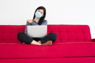 Yüz maskesi takan yorgun bir kadın, bilgisayarla uğraşmaktan yorgun düşmüş boynu ağrıyan kaslar, bilgisayarla uzun saatler çalıştıktan sonra ofis sendromu. Ofis sendromu ve sağlık konsepti.