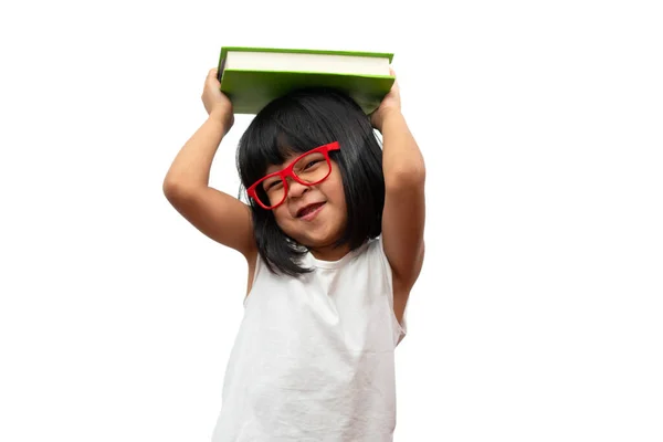 有趣而快乐的亚洲学龄前小女孩戴着红色眼镜 头上顶着一本绿色的书 背景是白色孤立的 学童的概念以及小学和学前教育 家庭学校的教育 — 图库照片