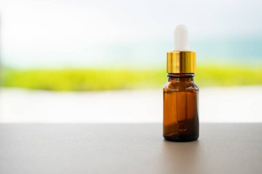 Masanın üzerinde damlatan kahverengi bir cam şişe. Aroma yağı, kozmetik ve güzellik kavramı.