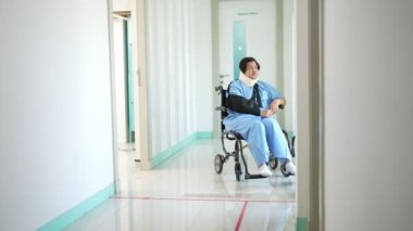 Kazadan sonra tekerlekli sandalyedeki Asyalı hasta ve doktorla konuşurken, fizyoterapist hastaya kaza durumunda nasıl iyileşeceğini ve sigortanın nasıl karşılanacağını açıklar.