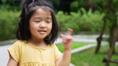 Asyalı komik bir çocuğun portresi 4 yaşında ve saçlarını toplaması ve ellerini çenesine koyması ve düşünme pozu vermesi, o mutluluk, gençlikte parlaklık, eğitim kavramı.