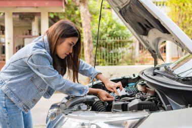 Kızgın Asyalı kadın ve yolda bir araba arızasından sonra cep telefonuyla yardım istiyor. Araç motoru sorunu veya kaza kavramı ve profesyonel tamirciden acil yardım