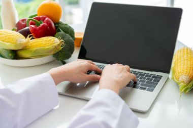 Asyalı gülümseyen kadın beslenme uzmanının portresi hasta ya da kilo verme tavsiyesi için dengeli bir diyet planı için dizüstü bilgisayarda daktilo ediyor. Sağlıklı yaşam biçimi, sağlıklı yemek, diyet