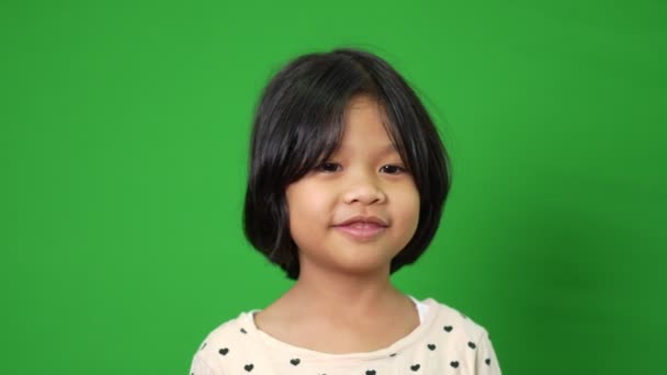 在绿色的画面背景上描绘着快乐 微笑和滑稽的亚洲小女孩 一个小孩看着相机 学龄前儿童的梦想充满了精力 感觉健康和好的概念 — 图库视频影像
