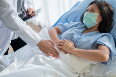 Bir grup doktor, hasta kadının hasta yatağında yatmasına ve karın ağrısına dayanmasına yardım etmeye çalışıyor. Adet, ishal ya da hazımsızlıktan kaynaklanan karın ağrısı. Hastalık ve sağlık hizmeti kavramı