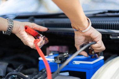 Araba aküsünü şarj etmek için akü kablosu tutan tamircinin seçici odak noktası araba aküsü, servis motoru konsepti