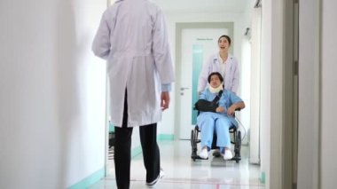 Kazadan sonra tekerlekli sandalyedeki Asyalı hasta ve doktorla konuşmak, hastayı tekerlekli sandalyeye iten cerrah, kazadan kaynaklanan ağrı.