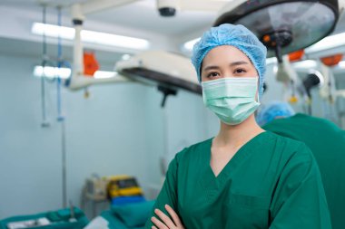 Hastane ameliyathanesinde kollarını kavuşturmuş, tıbbi maskeli Asyalı cerrah ve hemşire portresi. Profesyonel cerrahlar takımı. Sağlık hizmeti, acil tıbbi servis kavramı