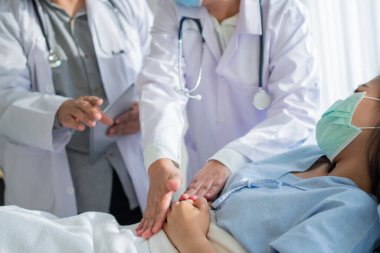 Bir grup doktor, hasta kadının hasta yatağında yatmasına ve karın ağrısına dayanmasına yardım etmeye çalışıyor. Adet, ishal ya da hazımsızlıktan kaynaklanan karın ağrısı. Hastalık ve sağlık hizmeti kavramı