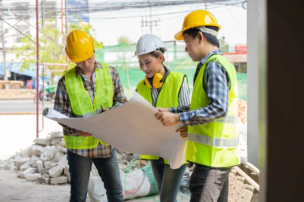 Asyalı mühendis ya da genç bayan mimar güvenlik için bir kask taktı ve bir inşaat fabrikası projesi için müteahhitle konuştu: Takım çalışması kavramı, liderlik kavramı..