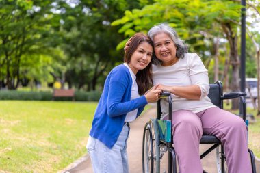 Tekerlekli sandalyedeki hastayla ilgilenen Asyalı dikkatli bir bakıcı ya da hemşire. Bakıcının, birikimin ve sağlık sigortasının özenle mutlu emeklilik kavramı. Mutlu bir aile.