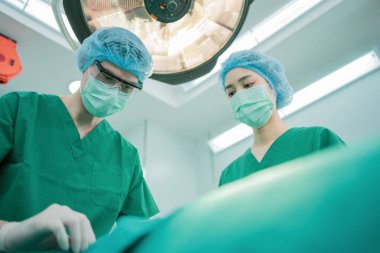 Profesyonel cerrahlar için düşük açılı ameliyat ekibi ameliyathanede, cerrah, asistan ve hemşireler bir hastaya, sağlık kanseri ve hastalık tedavi konseptinde ameliyat yapıyor.