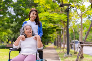 Tekerlekli sandalyedeki hastayla ilgilenen Asyalı dikkatli bir bakıcı ya da hemşire. Bakıcının, birikimin ve sağlık sigortasının özenle mutlu emeklilik kavramı. Mutlu bir aile.