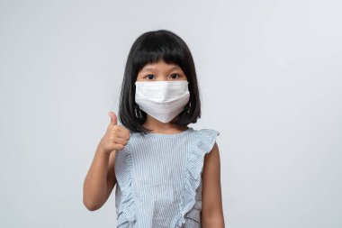 Korumacı maskeli Asyalı kız çocuğunun portresi yeni okul yılına pandemik kısıtlamalarla hazır. Çocuğun okula geri dönmesi ve yeni normal yaşam tarzı.