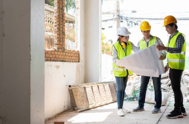 Asyalı mühendis ya da genç bayan mimar güvenlik için bir kask taktı ve bir inşaat fabrikası projesi için müteahhitle konuştu: Takım çalışması kavramı, liderlik kavramı..