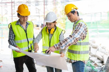 Asyalı mühendis ya da genç bayan mimar güvenlik için bir kask taktı ve bir inşaat fabrikası projesi için müteahhitle konuştu: Takım çalışması kavramı, liderlik kavramı..