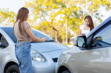İki sürücü, fotoğraf çekip sigorta göndermeden önce araba kazasından sonra hasar kontrolü yapıyor. Bir sigorta şirketine fotoğraf ve kanıt gönderdikten sonra online kaza sigortası iddiası.