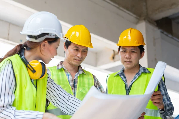 Asyalı mühendis ya da genç bayan mimar güvenlik için bir kask taktı ve bir inşaat fabrikası projesi için müteahhitle konuştu: Takım çalışması kavramı, liderlik kavramı..