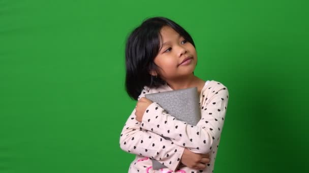 可爱的亚洲女学生7 8岁的画像 看着摄像机站着 拿着绿色屏幕背景的书 思考着新的想法 聪明的孩子喜欢用纸质书学习 — 图库视频影像
