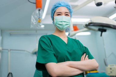 Hastane ameliyathanesinde kollarını kavuşturmuş, tıbbi maskeli Asyalı cerrah ve hemşire portresi. Profesyonel cerrahlar takımı. Sağlık hizmeti, acil tıbbi servis kavramı