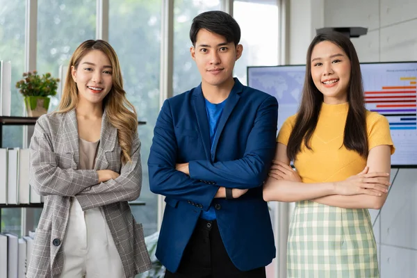 Group of Asia young entrepreneurs creative people looking at camera and smiling after brainstorming, working together in the office. Stratup business team discusses and shares ideas for new projects.