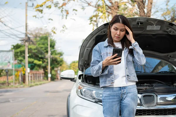 怒っているアジアの女性と路上で車の故障後の支援を求める携帯電話を使用しています 車両エンジンの問題や事故や専門の機械工からの緊急支援の概念 — ストック写真