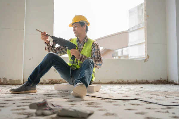 Construction worker Using an electric jackhammer to drill perforator equipment making holes before pouring the floor to be strong at construction site, Concept of worker and residential building.