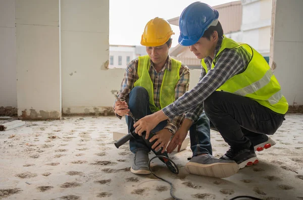 Engineer teaching worker for use electric jackhammer for perforator equipment making holes the floor to be strong at construction site, Concept of worker and residential building