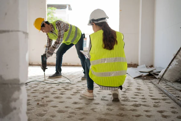 Engineer checking worker using an electric jackhammer to drill perforator equipment making holes before pouring the floor to be strong at construction site, Concept of worker and residential building