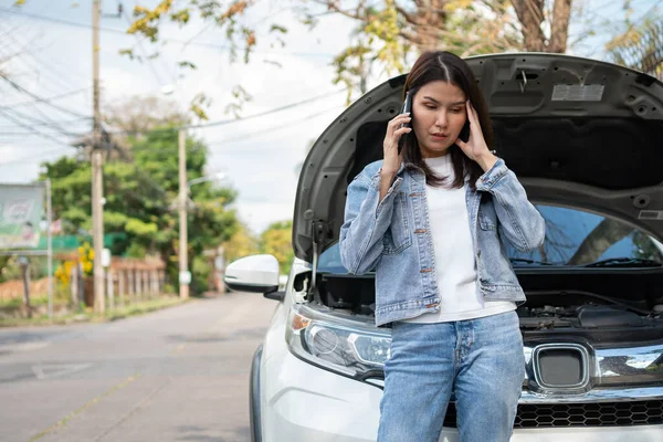 怒っているアジアの女性と路上で車の故障後の支援を求める携帯電話を使用しています 車両エンジンの問題や事故や専門の機械工からの緊急支援の概念 — ストック写真