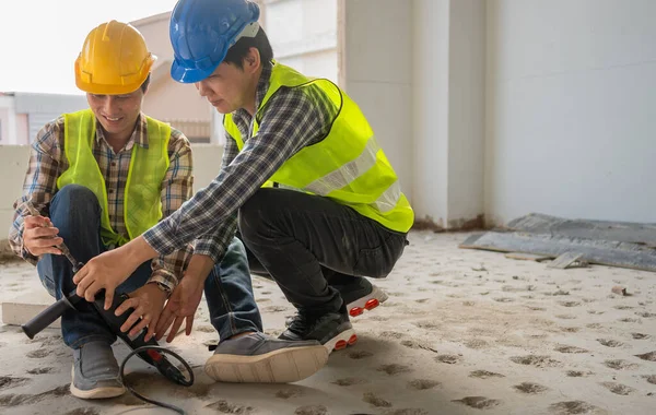 Engineer teaching worker for use electric jackhammer for perforator equipment making holes the floor to be strong at construction site, Concept of worker and residential building