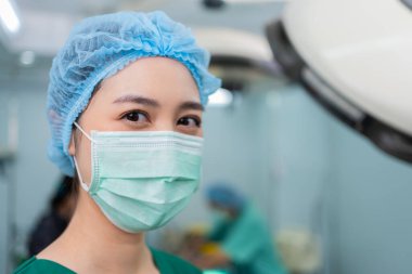Hastanedeki ameliyathanede duran tıbbi maskeli Asyalı kadın cerrahın portresi. Profesyonel cerrahlar takımı. Sağlık hizmeti, acil tıbbi servis kavramı