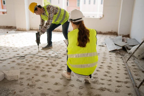 Engineer checking worker using an electric jackhammer to drill perforator equipment making holes before pouring the floor to be strong at construction site, Concept of worker and residential building