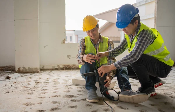 Engineer teaching worker for use electric jackhammer for perforator equipment making holes the floor to be strong at construction site, Concept of worker and residential building