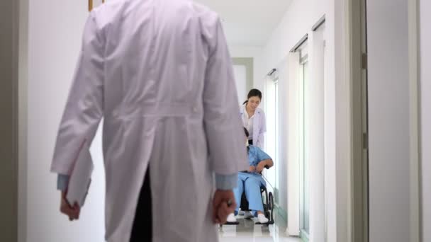 亚洲妇女在事故后坐轮椅 与医生交谈 外科医生将病人推上轮椅 因意外受伤而感到疼痛 — 图库视频影像