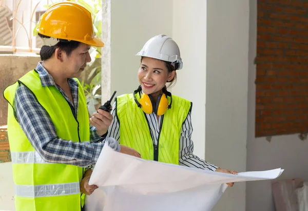 Asian engineer or Young Female Architect put on a helmet for safety and talk with a contractor on a construction building factory project, Concept of Teamwork, Leadership concept.