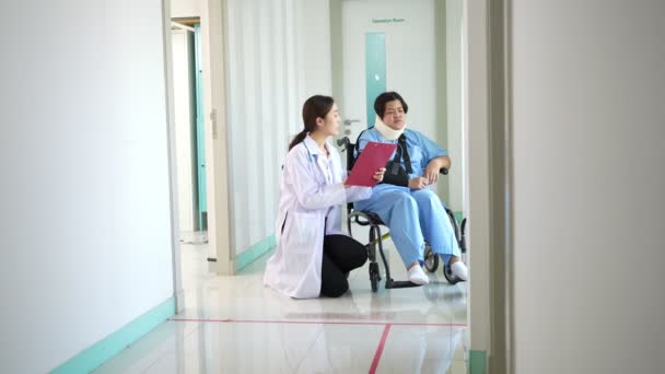 亚洲女性轮椅患者在事故后与医生 理疗师解释如何康复 外科医生将患者推上轮椅 因意外事故受伤而感到疼痛 — 图库视频影像