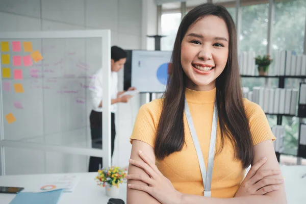 Young Asian Happy Businesswoman or intern in Modern Office background is Colleagues discuss with new startup project Idea. Empowered Digital Entrepreneur Works on Startup Project