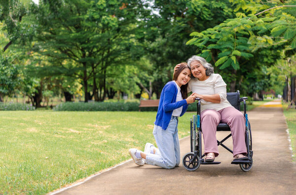 Asian careful caregiver or nurse taking care of the patient in a wheelchair.  Concept of happy retirement with care from a caregiver and Savings and senior health insurance, a Happy family