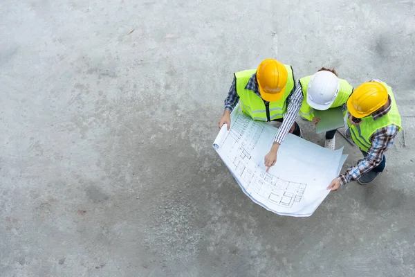 Top view of Asian engineer or Young Female Architect put on a helmet for safety and talk with a contractor on a construction building factory project, Concept of Teamwork, Leadership concept.