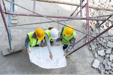 Top view of Asian engineer or Young Female Architect put on a helmet for safety and talk with a contractor on a construction building factory project, Concept of Teamwork, Leadership concept.
