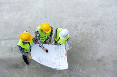 Top view of Asian engineer or Young Female Architect put on a helmet for safety and talk with a contractor on a construction building factory project, Concept of Teamwork, Leadership concept.