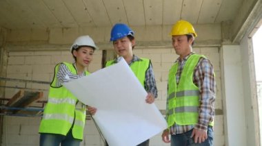 Bir grup Asyalı mühendis ya da genç bayan mimar güvenlik için bir kask taktılar ve bir inşaat fabrikası projesi için müteahhitle görüştüler: Takım çalışması kavramı, liderlik kavramı..