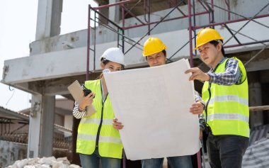 Asyalı mühendis ya da genç bayan mimar güvenlik için bir kask taktı ve bir inşaat fabrikası projesi için müteahhitle konuştu: Takım çalışması kavramı, liderlik kavramı..