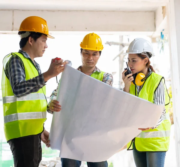 Asian engineer or Young Female Architect put on a helmet for safety and talk with a contractor on a construction building factory project, Concept of Teamwork, Leadership concept.