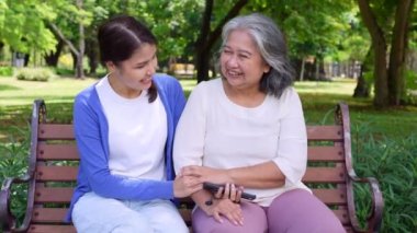 Happy senior mother with gray hair talk and laugh with daughter or caregiver in the park. Concept of happy retirement with care from a caregiver and Savings and senior health insurance, senior care