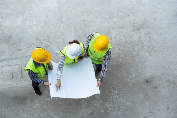 Top view of Asian engineer or Young Female Architect put on a helmet for safety and talk with a contractor on a construction building factory project, Concept of Teamwork, Leadership concept.